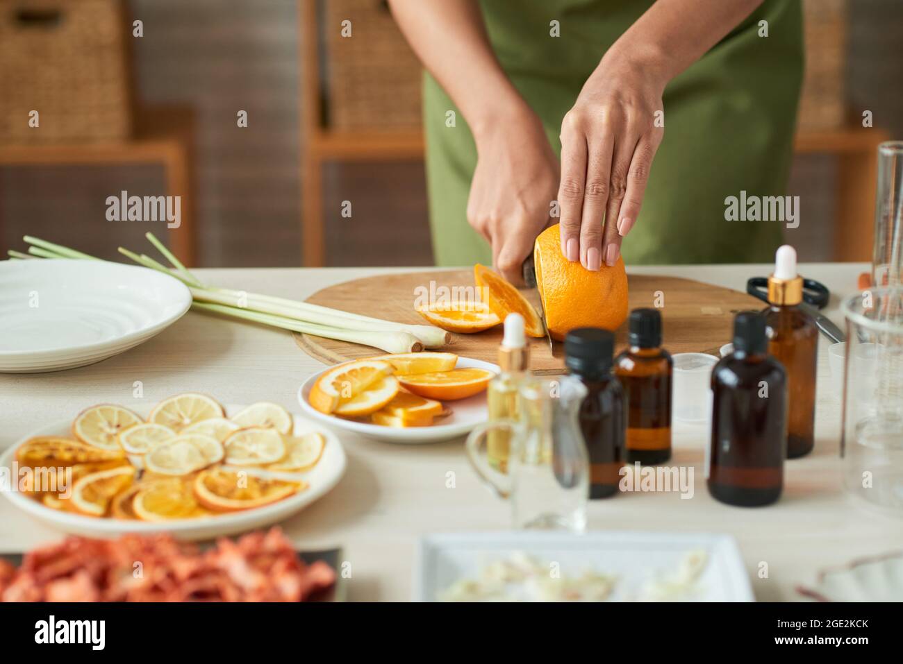 Nahaufnahme einer Frau in der Schürze, die orange wehn schneidet und dünne Scheiben für die Herstellung von oragnischer Seife vorstellt Stockfoto
