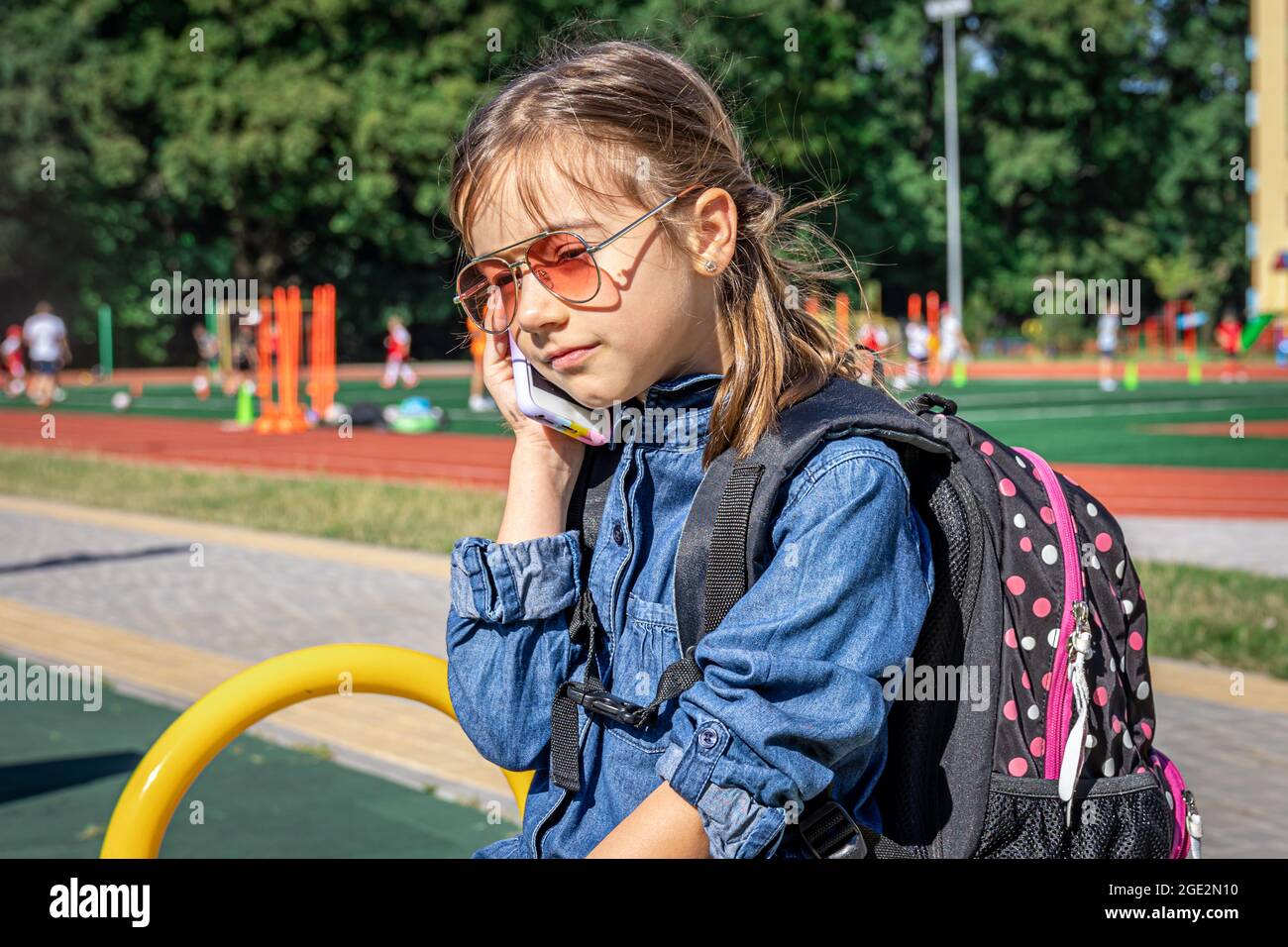 Ein kleines Mädchen, eine Grundschülerin in Sonnenbrillen telefonieren, nur reden, Kommunikation. Stockfoto