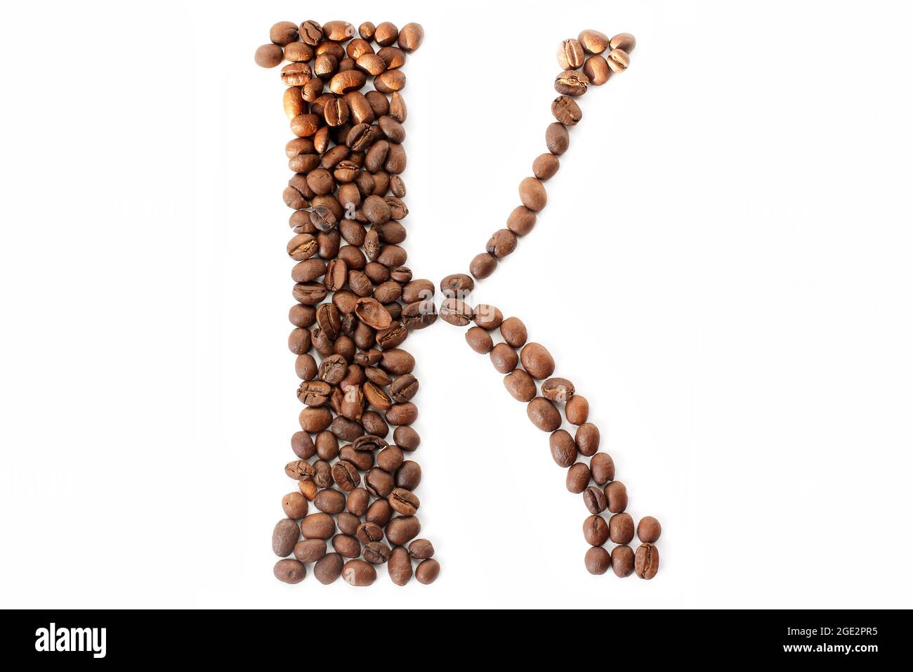 Kaffeebohnen. Buchstabe K aus Kaffeebohnen auf weißem Hintergrund. Braun Stockfoto