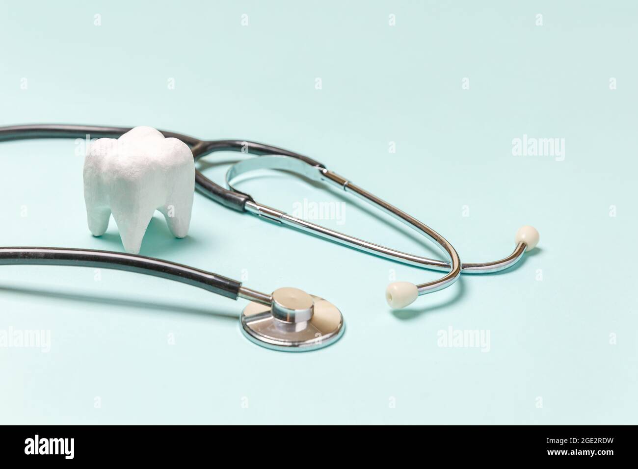 Gesundheit Zahnpflege Konzept. Medizingeräte Stethoskop weiß gesunden Zahn auf pastellblauem Hintergrund isoliert. Instrumentengerät für Zahnarzt Stockfoto
