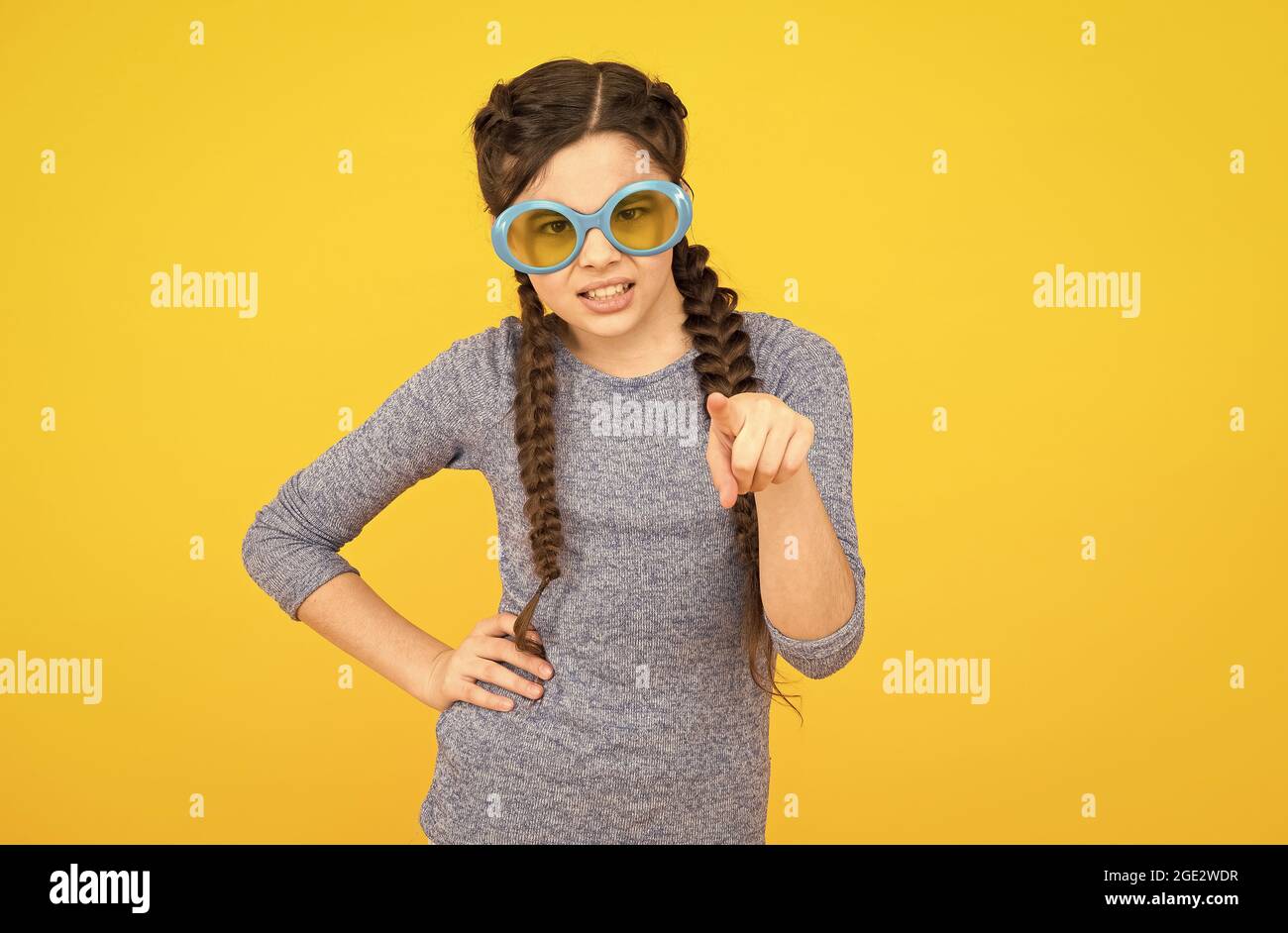 Sonnenbrillen sind gesundheitliche Notwendigkeit. Unzufrieden Kind gelben Hintergrund. Get Party started. Kid Zeigefinger. Porträt des Mädchens in lustigen Brillen. Jung Stockfoto