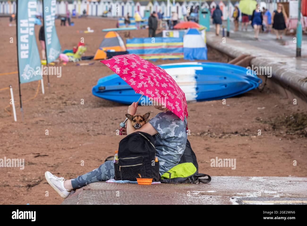 Urlauber trotzen den Elementen am Goodrington North Beach in Paignton, Devon, der von Gewitterschauern getroffen wurde und einige Touristen dazu zwingt, für Deckung zu laufen, Großbritannien. Stockfoto