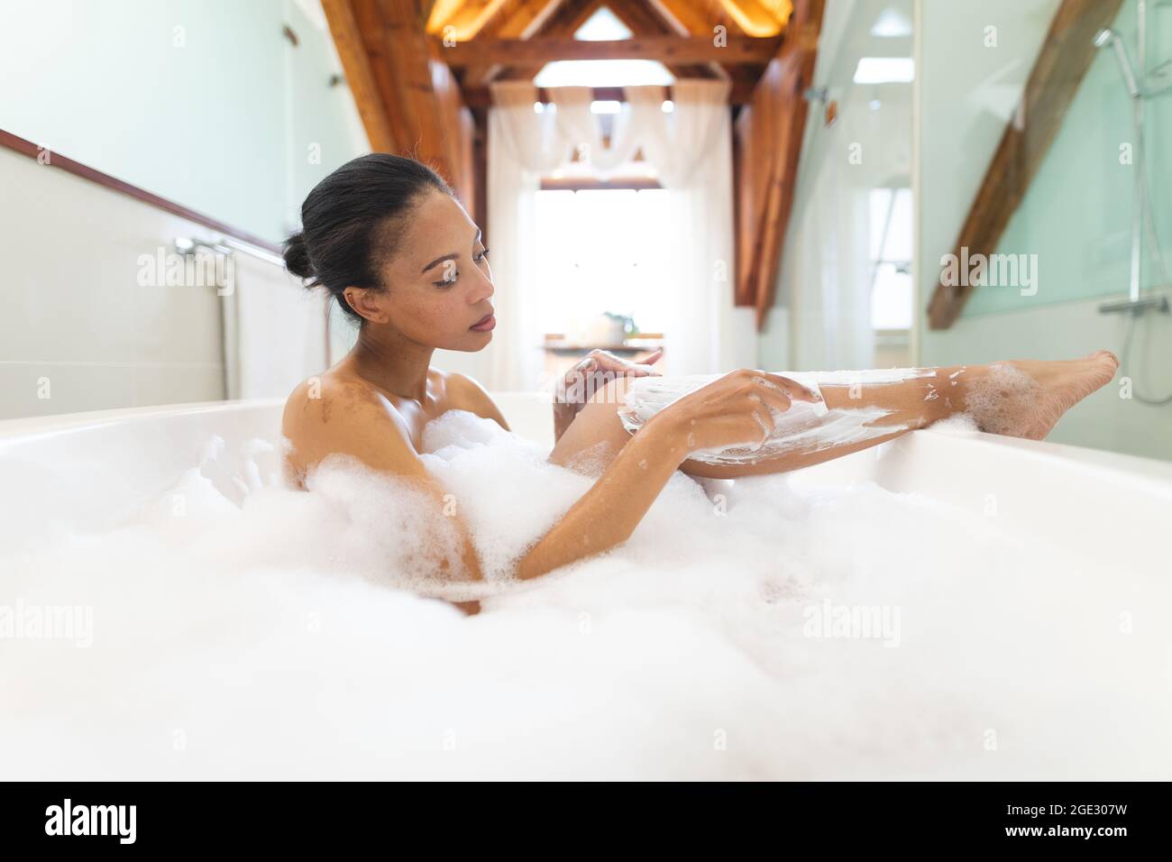 Frau mit gemischter Rasse im Badezimmer, die sich eine Badewanne und die  Beine rasieren ließ Stockfotografie - Alamy