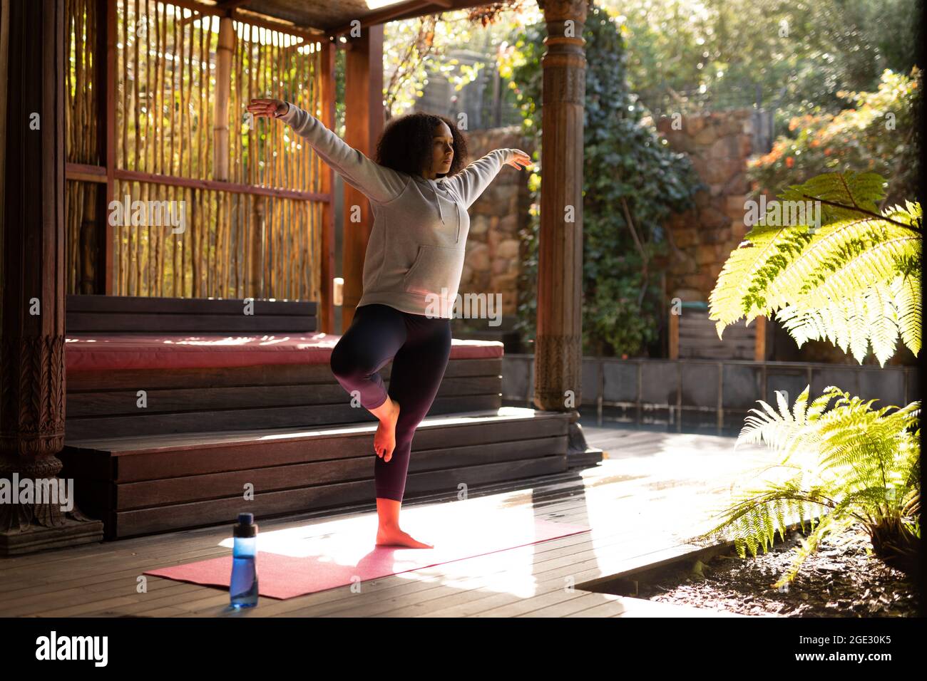 Frau mit gemischter Rasse, die Sportkleidung trägt und Yoga auf einer Yogamatte praktiziert Stockfoto