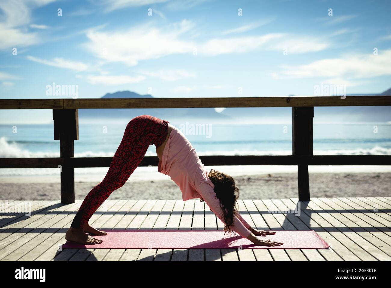 Frau mit gemischter Rasse, die an sonnigen Tagen am Meer Yoga praktiziert Stockfoto