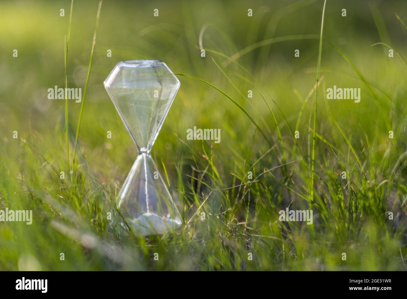 Eine Sanduhr auf einem Hintergrund aus grünem Gras. Stockfoto