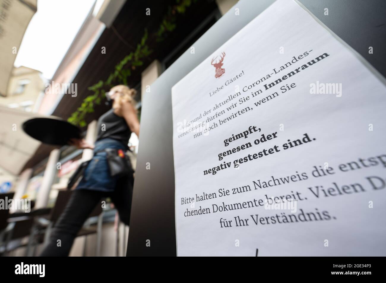 Stuttgart, Deutschland. August 2021. Eine Kellnerin geht an einer Notiz am  Eingang eines Restaurants vorbei. Unabhängig von der Zahl der neuen  Corona-Infektionen sollten die Menschen im Südwesten wieder am  gesellschaftlichen Leben teilnehmen