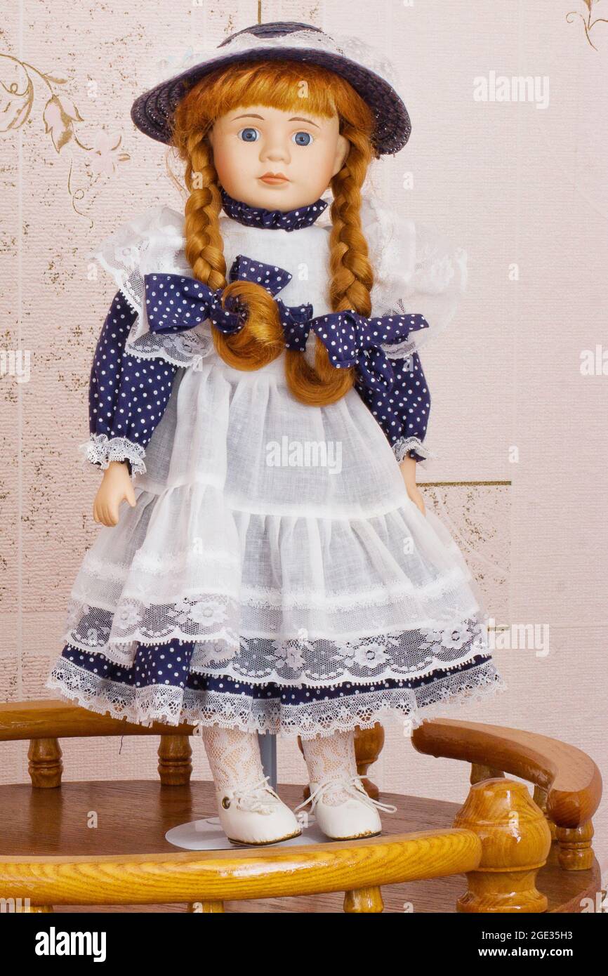 Wunderschöne Puppe. Puppe in einem blauen Kleid mit Schürze Stockfoto