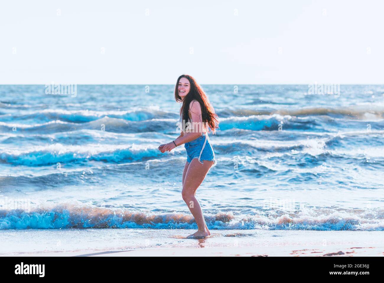 Junge Frau, die im Sommer im Meer spielt. Frau, die im Meerwasser genießt. Fröhliche junge Frau, die Spaß am Strand hat. Sie ist entspannt im Meerwasser und Stockfoto