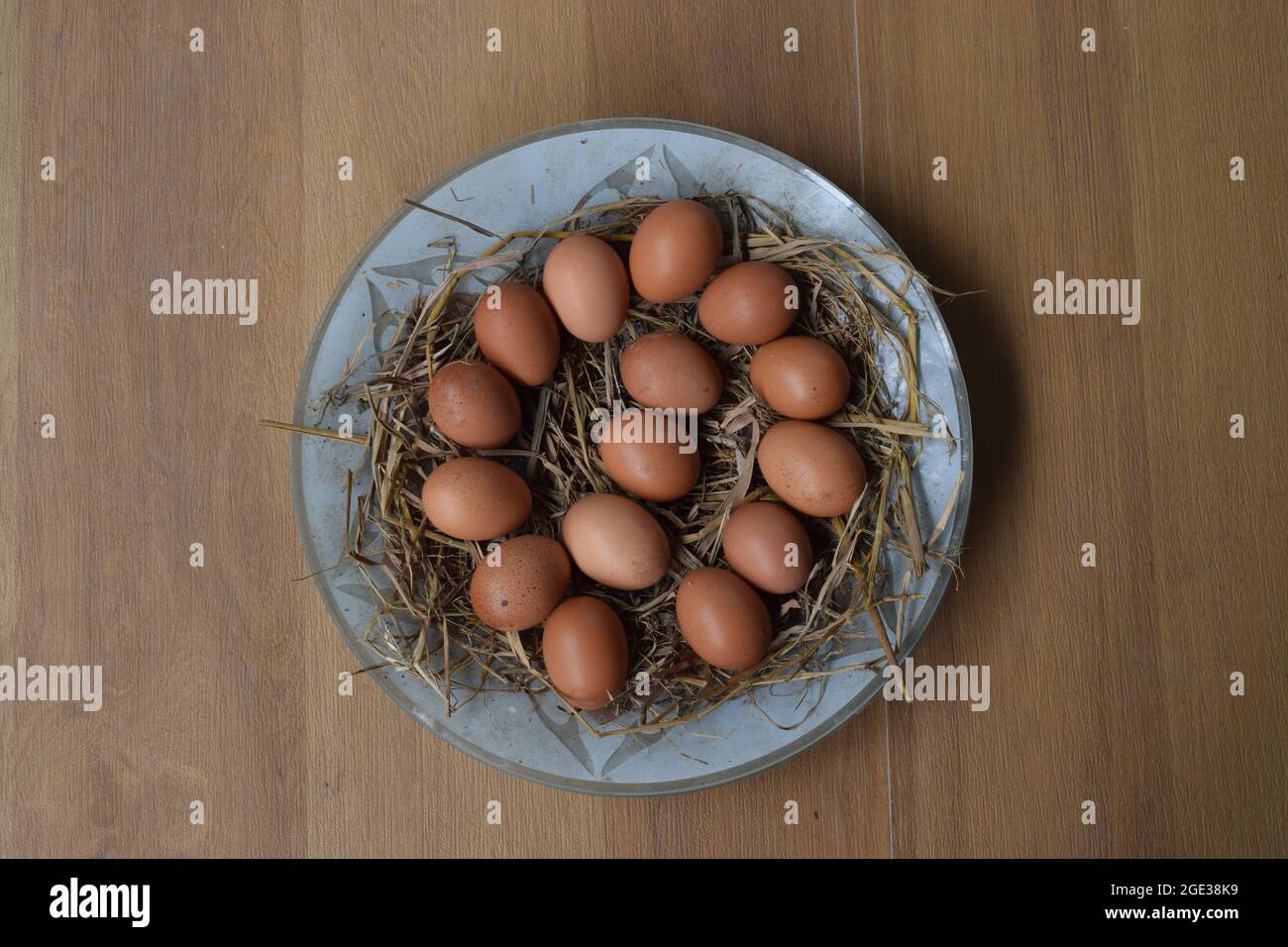 Frische Eier auf dem Teller, frische Eiersammlung mit Eierschale und Strohschicht auf dem Teller im Fliesenhintergrund, heiße rohe Eier Cluster, Cluster von Eiern Stockfoto