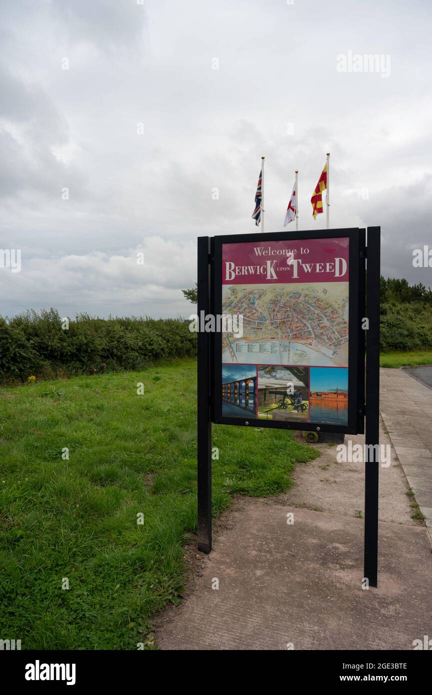 Berwick upon Tweed-Schild an der englischen Grenze zu Schottland. Flaggen im Hintergrund, Gras und Pfad unten und zur Seite des Schildes. Keine Personen. Stockfoto