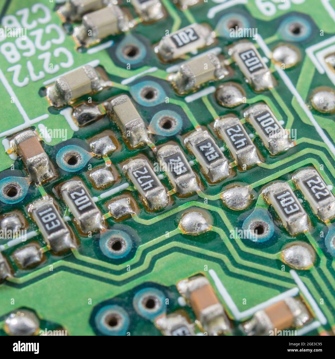 Makroaufnahme von elektronischen SMD-/SMD-Widerständen (schwarz) und Kondensatoren auf der leiterplatte sowie blauen Ringen mit herkömmlichem Durchgangslöten Stockfoto
