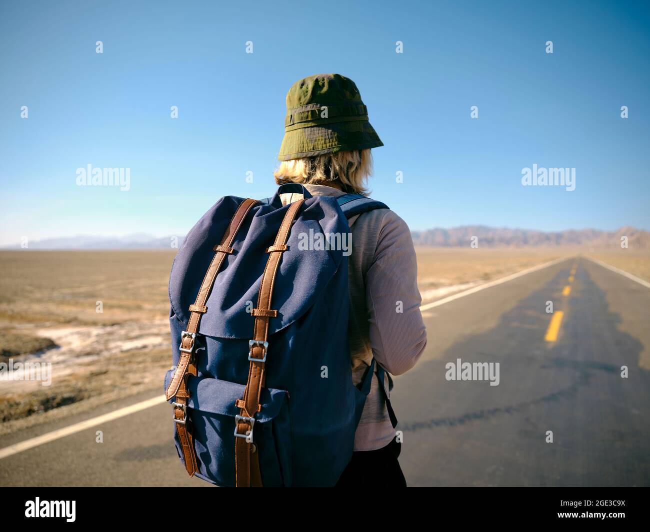 Rückansicht einer asiatischen Backpacker-Frau, die auf einem leeren Highway läuft Stockfoto