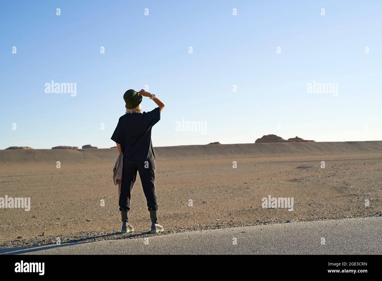 Rückansicht einer asiatischen Frau, die unter blauem Himmel in der Wüste gobi den Horizont sieht Stockfoto