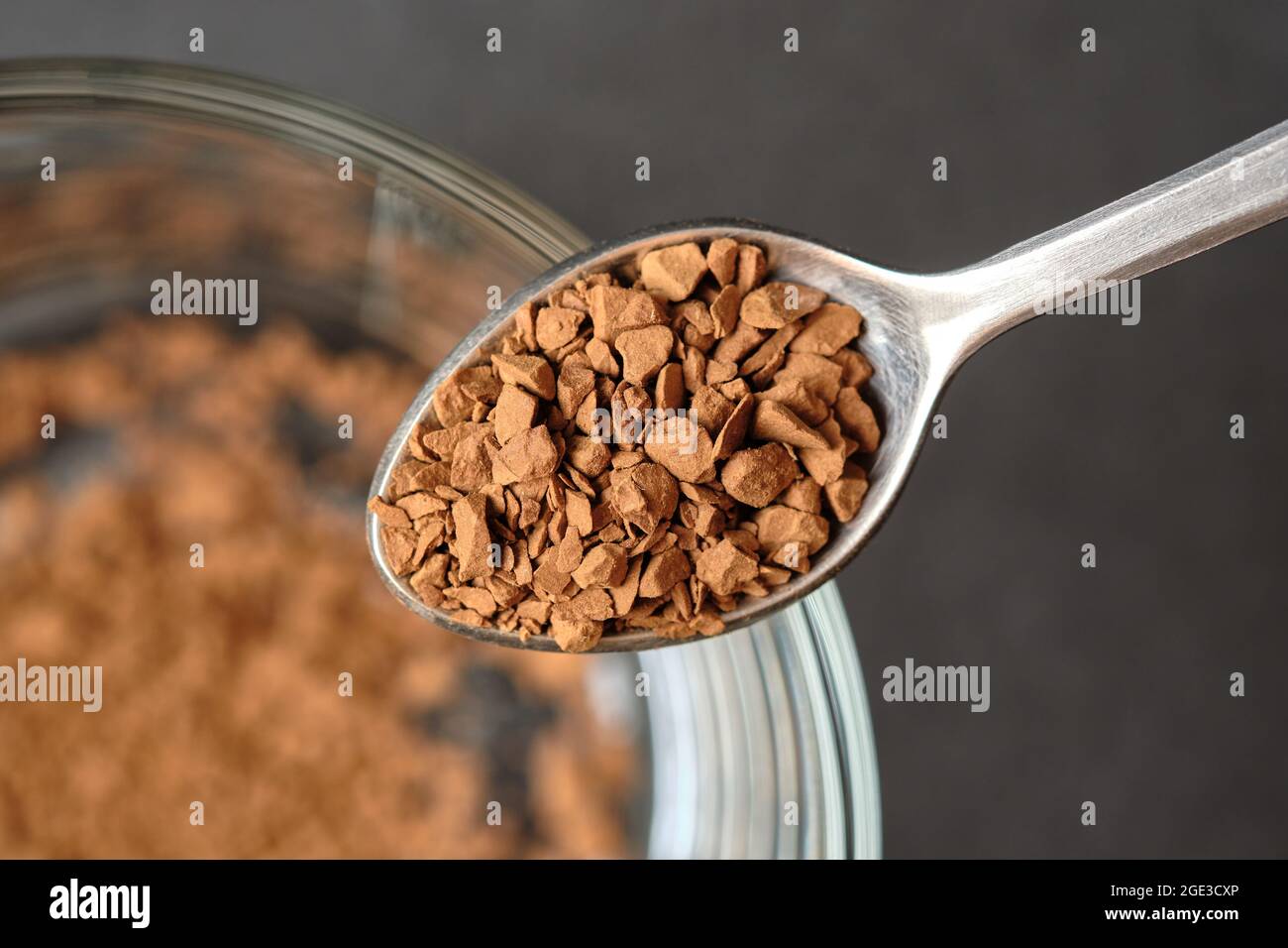 Gefriergetrockneter Instant-Kaffee auf Teelöffel mit Glas-Kaffeetasse Hintergrund. Stockfoto
