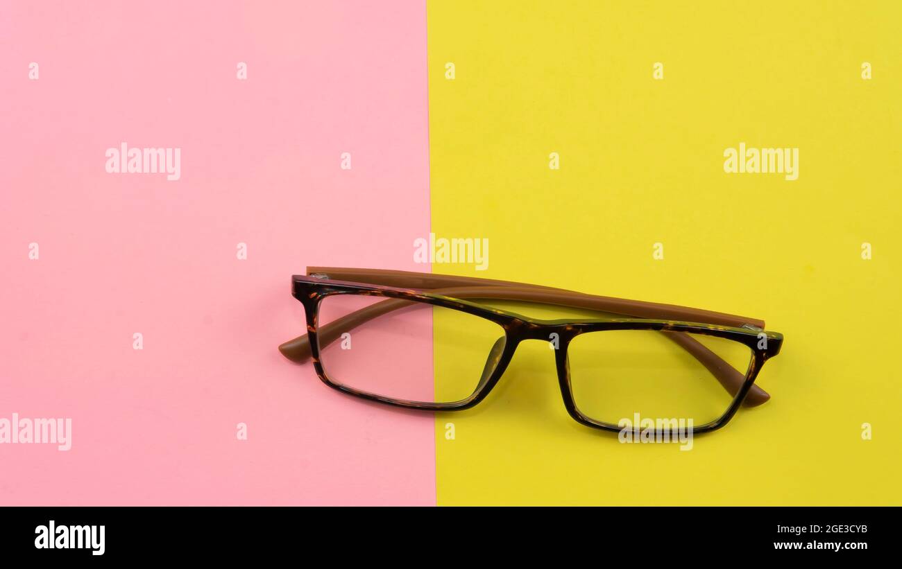 Ein Augenpflegekonzept. Die Seher konzentrieren sich auf eine Brille auf einem gelben und rosa Hintergrund Stockfoto
