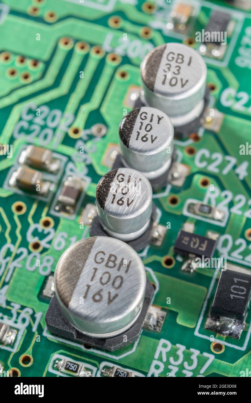 Nahaufnahme einer Reihe solider SMD-V-Chip-Hybrid-Aluminium-Elektrolytkondensatoren auf der leiterplatte mit schwarzer (minus) Polaritätsmarkierung. Marken nicht identifiziert Stockfoto