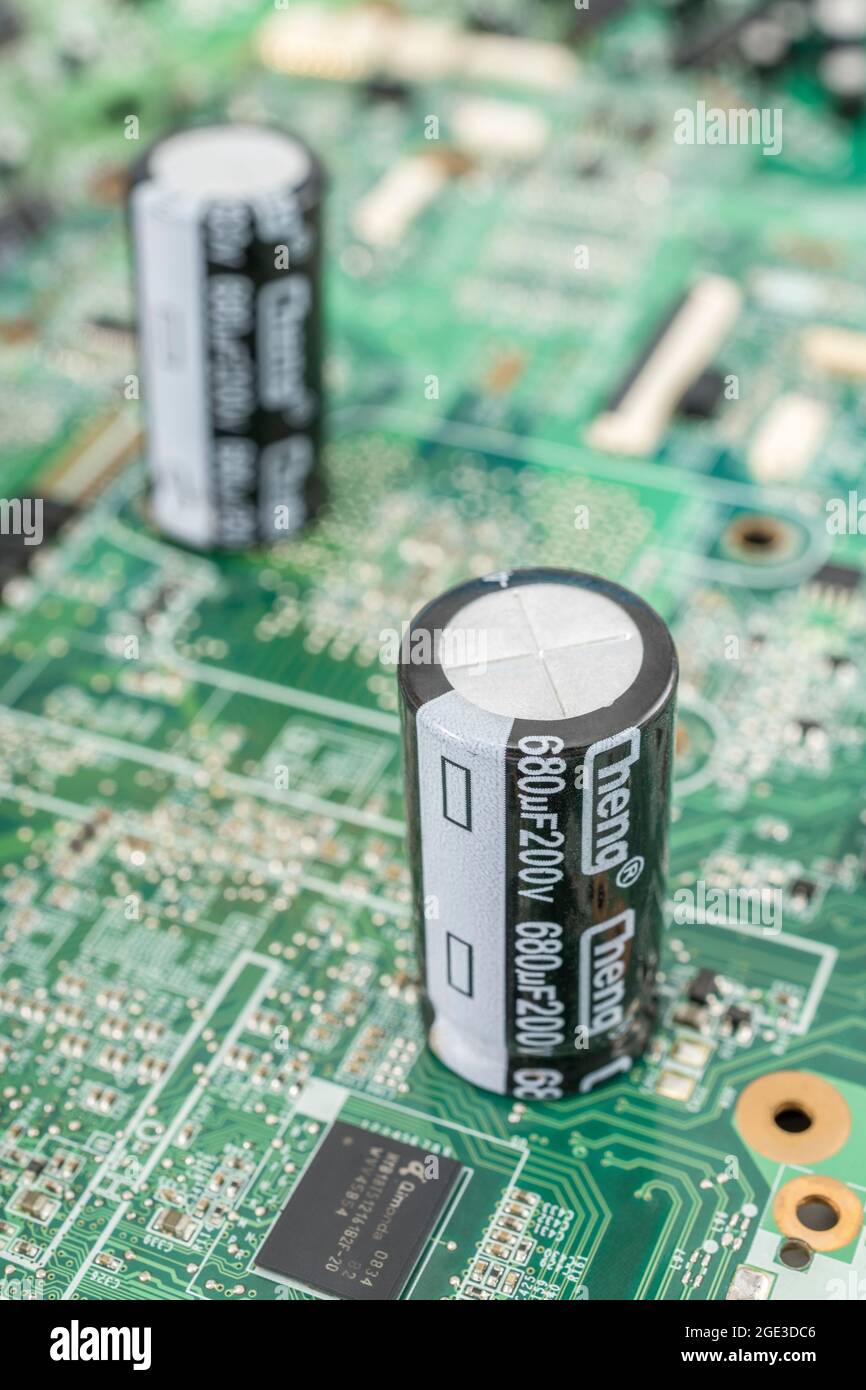 Nahaufnahme von 2 großen Aluminium-Elektrolytkondensatoren auf der leiterplatte. Zeigt die Teilespezifikation und -'ve Polaritätsmarkierungen an. Marke Cheng. Stockfoto