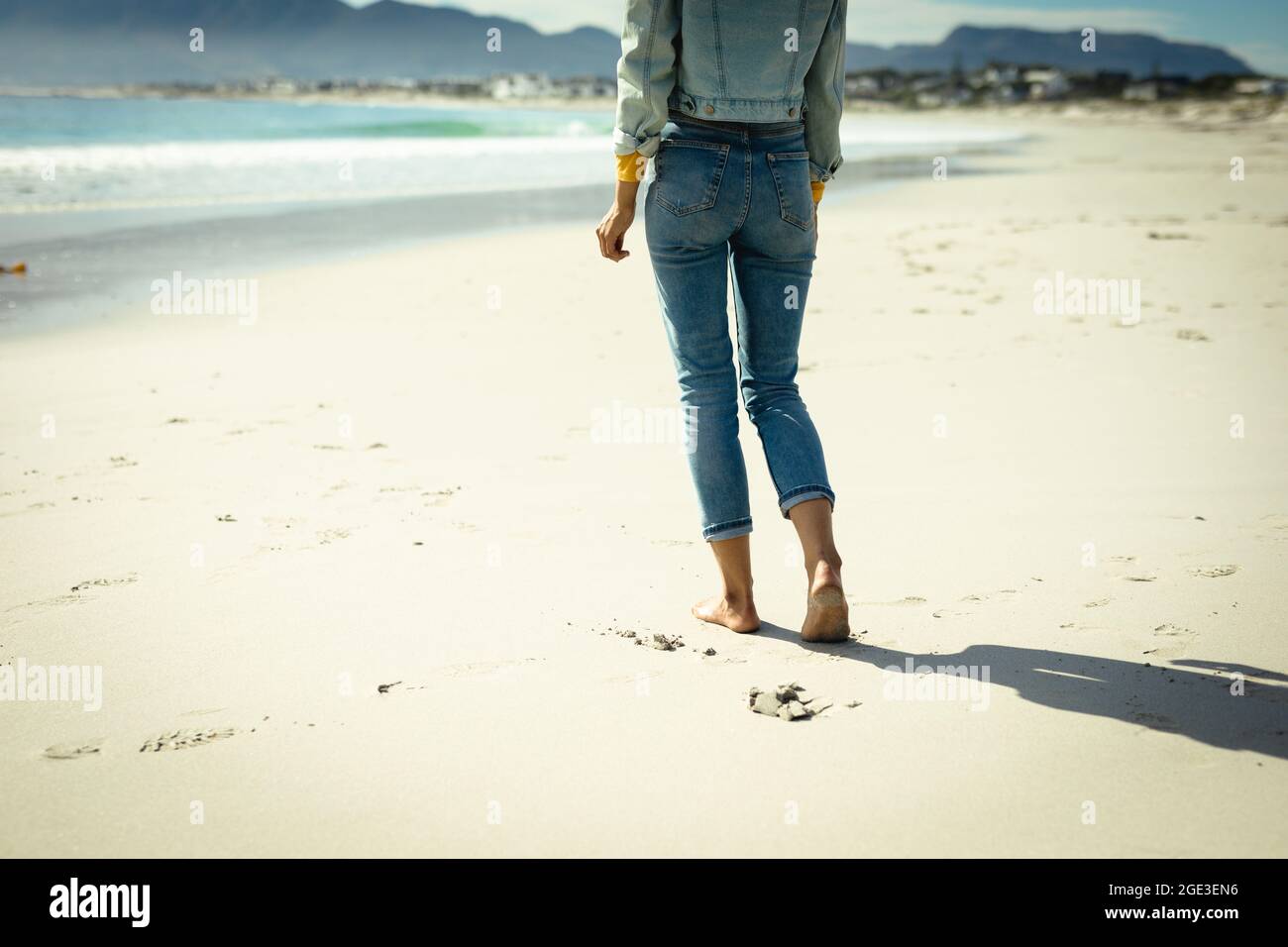 Frau mit gemischtem Rennen, die an einem sonnigen Tag am Strand spazieren geht Stockfoto
