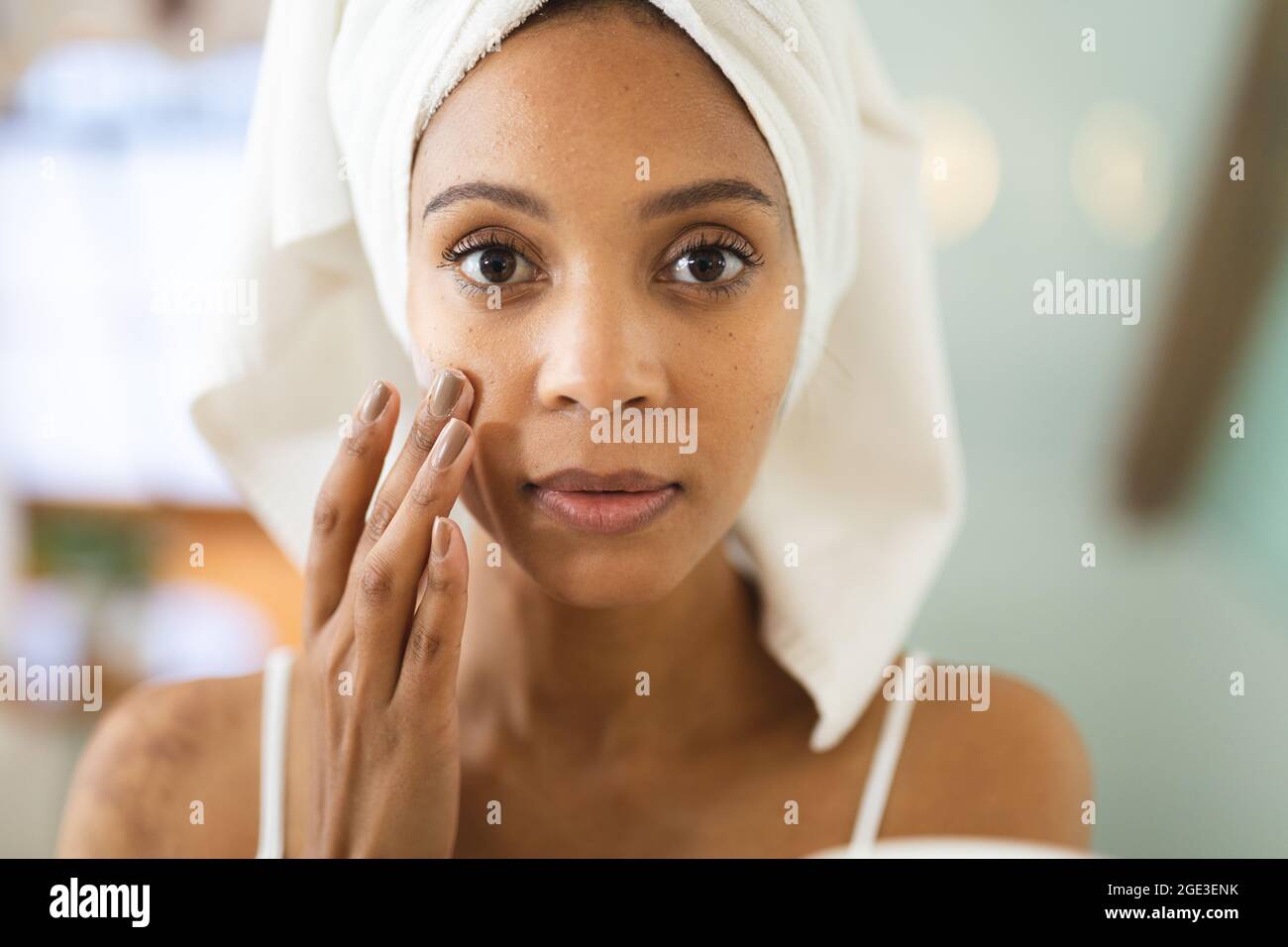Mixed Race Frau im Badezimmer Anwendung Gesichtscreme für die Hautpflege Stockfoto
