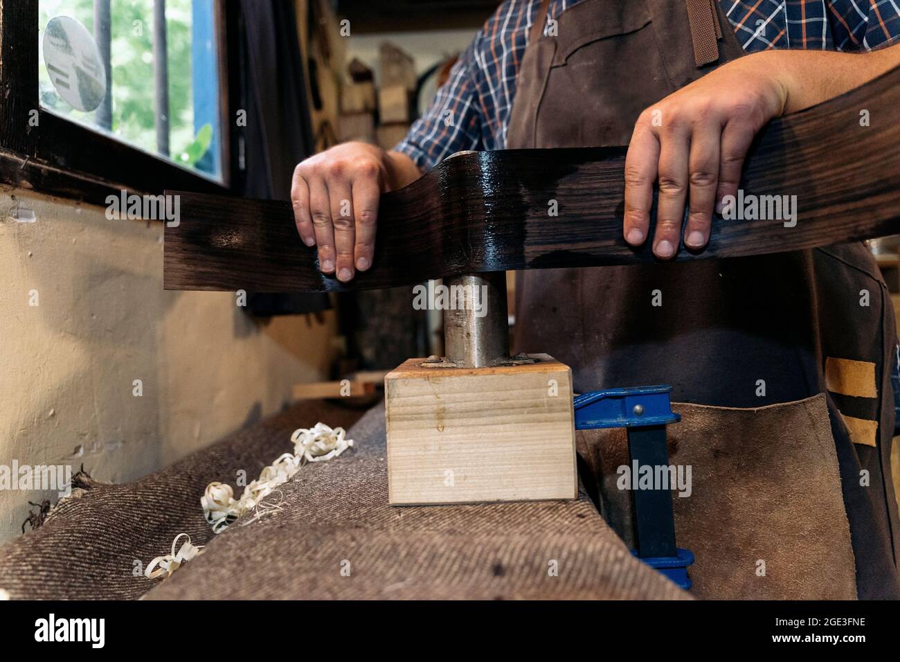 Unbekannter Geigenbauer, der in seiner Werkstatt eine Gitarre kreiert und Werkzeuge verwendet. Stockfoto