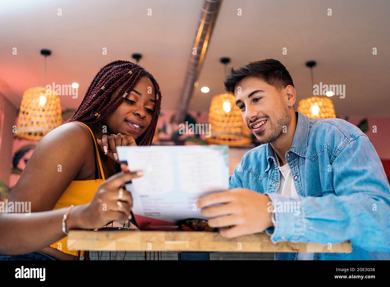 Multikulturelle Freunde sitzen in einem Restaurant und lesen gemeinsam das Menü. Stockfoto
