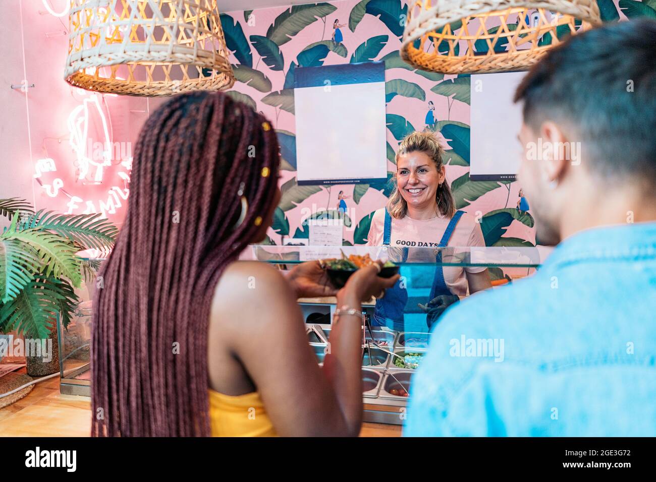 Unbekannte afroamerikanische Frau und ihre Freundin kaufen in einem coolen Restaurant eine Poke-Schüssel. Stockfoto