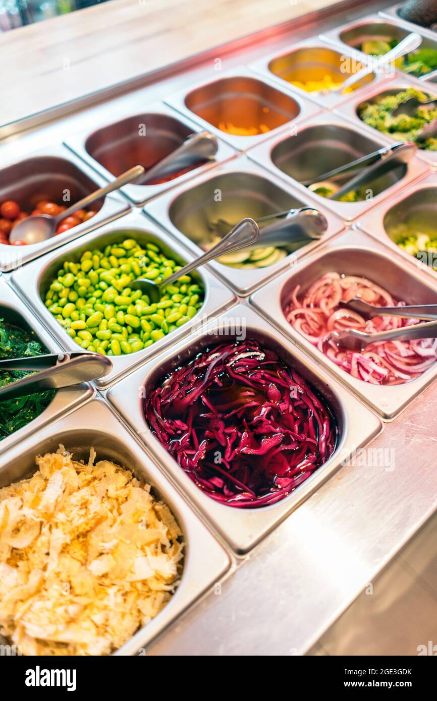 Blick auf verschiedene Zutaten, die in einem Restaurant verwendet werden, um eine leckere Poke-Schüssel zuzubereiten. Stockfoto