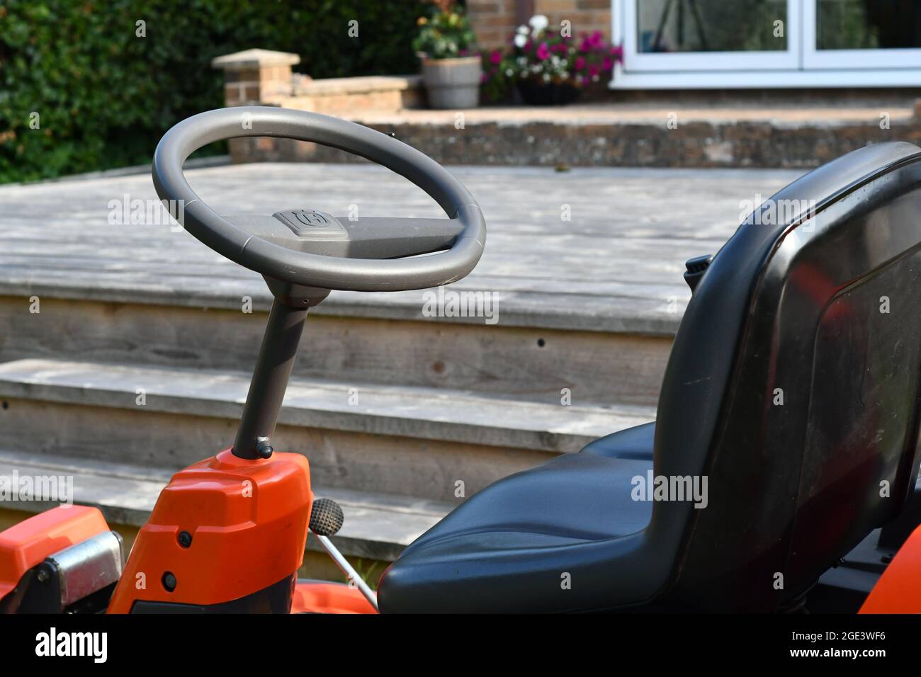 Eine Teilansicht einer Fahrt auf einem Rasenmäher und einer Gerüstplatte mit zweigeteilter Tür im Hintergrund Stockfoto