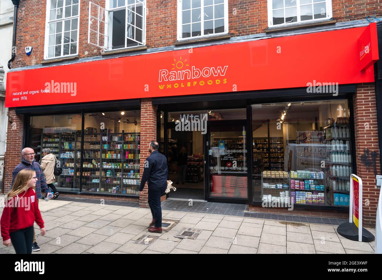 Rainbow Shop natürliches und biologisches Lebensmittelgeschäft in Davey Place mit leuchtend rotem Logo über der Ladenfront, an dem Menschen an einem sonnigen Tag vorbeilaufen Stockfoto