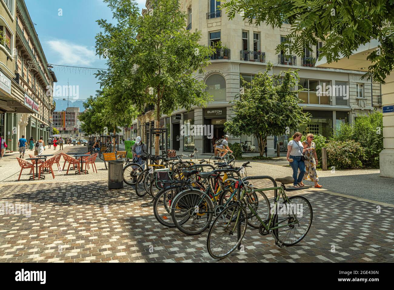 Touristen schlendern auf der Rue de la République in Grenoble. Fahrräder, die an einem sonnigen Sommertag im Schatten geparkt sind. Grenoble, Frankreich Stockfoto