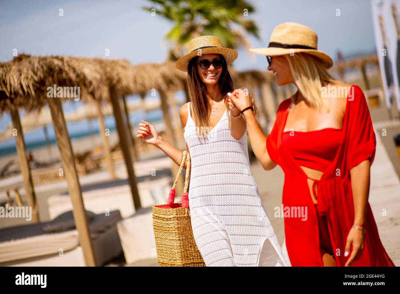 Zwei hübsche junge Frauen, die im Sommer an einem Strand spazieren Stockfoto