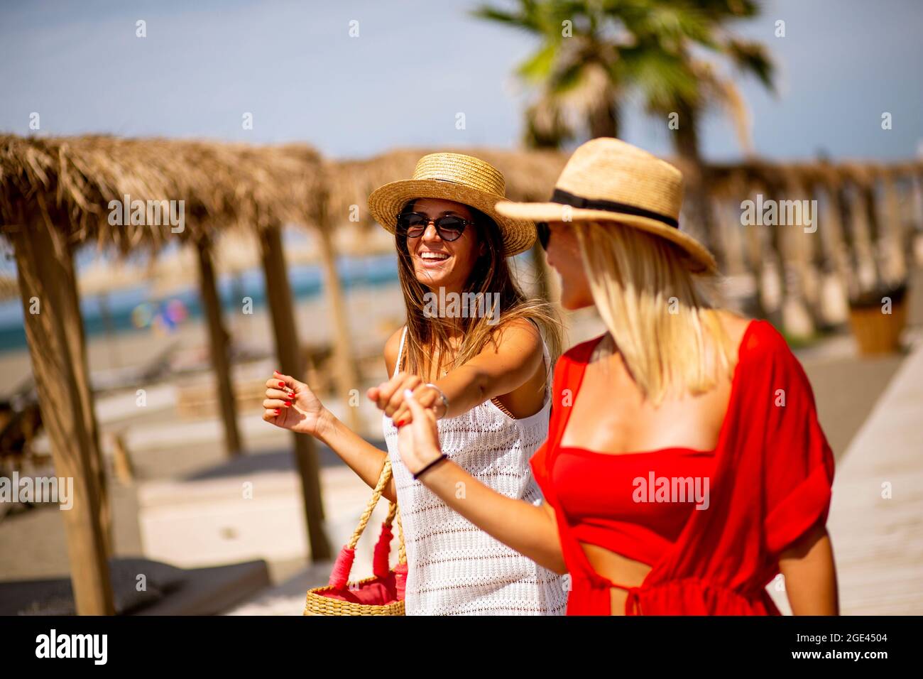 Zwei hübsche junge Frauen, die im Sommer an einem Strand spazieren Stockfoto