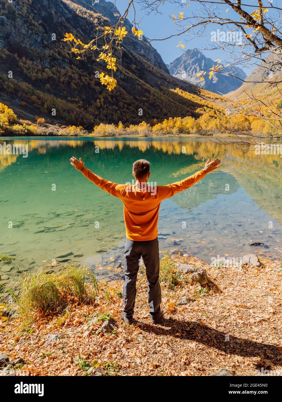 Glücklicher Mann am Kristallsee in herbstlichen Bergen. Bergsee und Wanderer Stockfoto