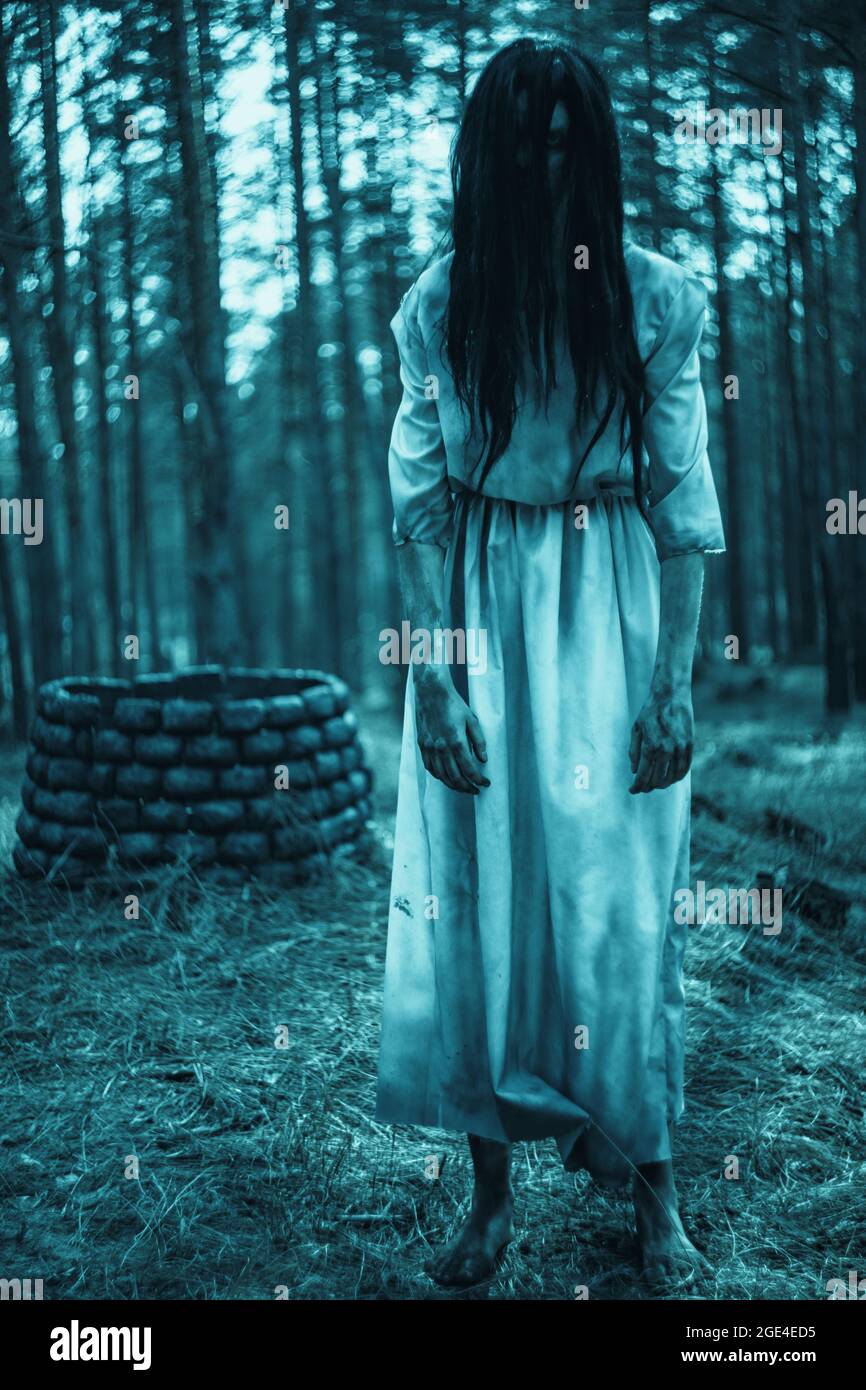 Mädchen mit langen schwarzen Haaren im Bild von gruseligen Geist Zombie  steht zwischen dunklen Wald vor dem Hintergrund von Stein gut  Stockfotografie - Alamy