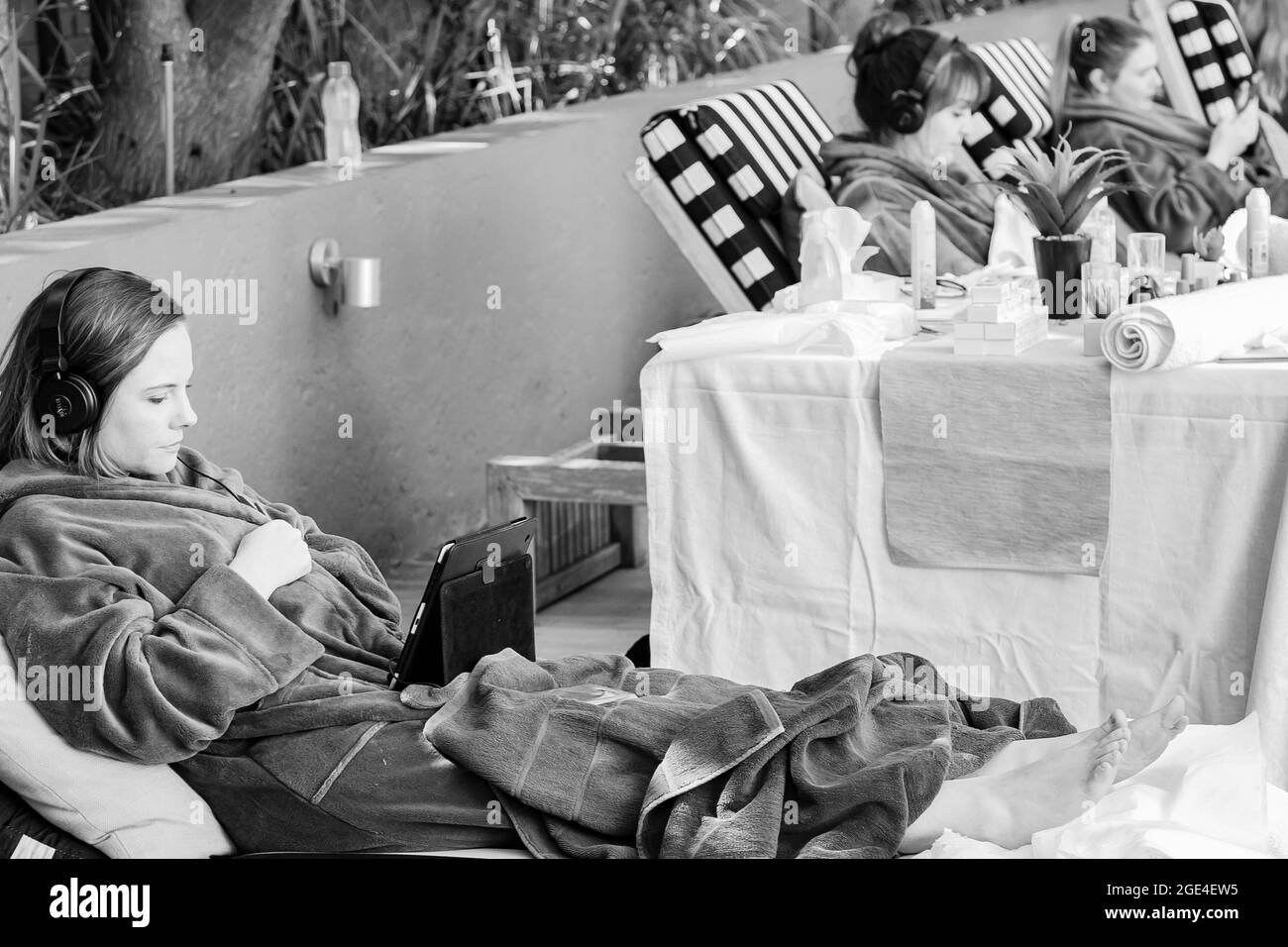 JOHANNESBURG, SÜDAFRIKA - 05. Jan 2021: Eine Graustufe einer Frau in einem Bademantel, die Streaming-Service auf einem Tablet-Computer in einem Spa-Resort beobachtet Stockfoto