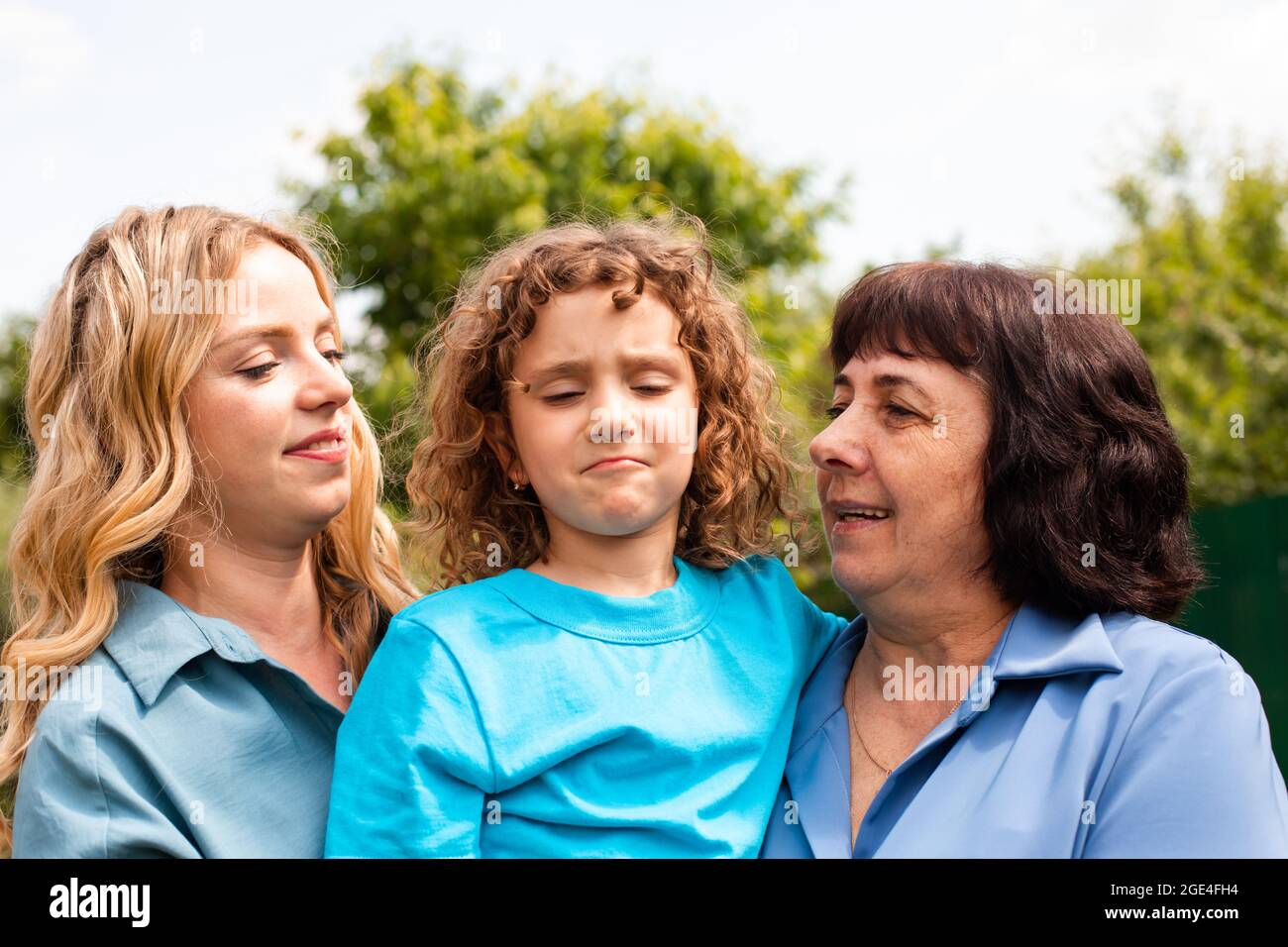 Nettes Mädchen umarmt Mutter und Großmutter im Freien Stockfoto