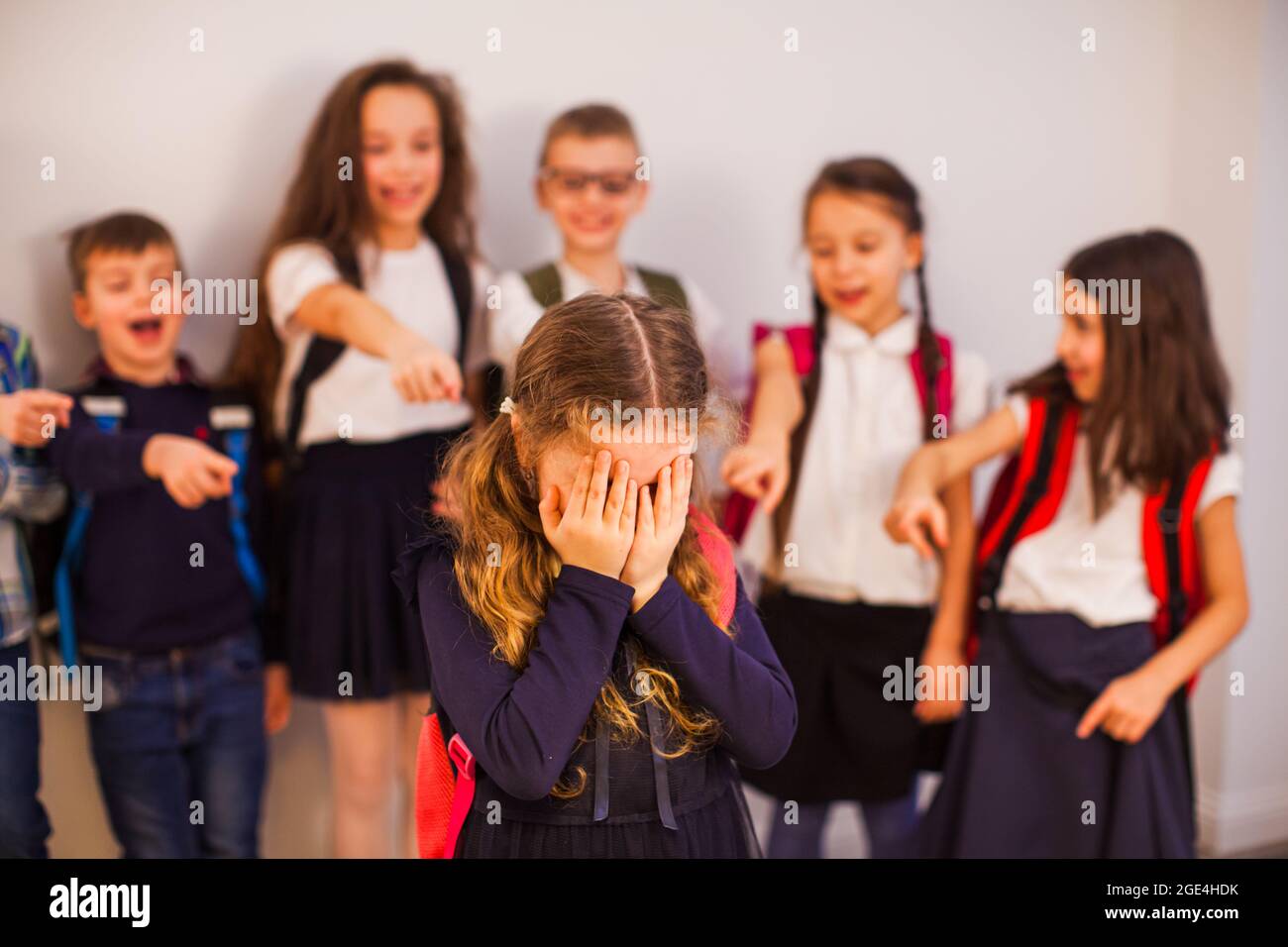 Die Klassenkameraden zeigen auf den Jungen und lachen ihn aus Stockfoto