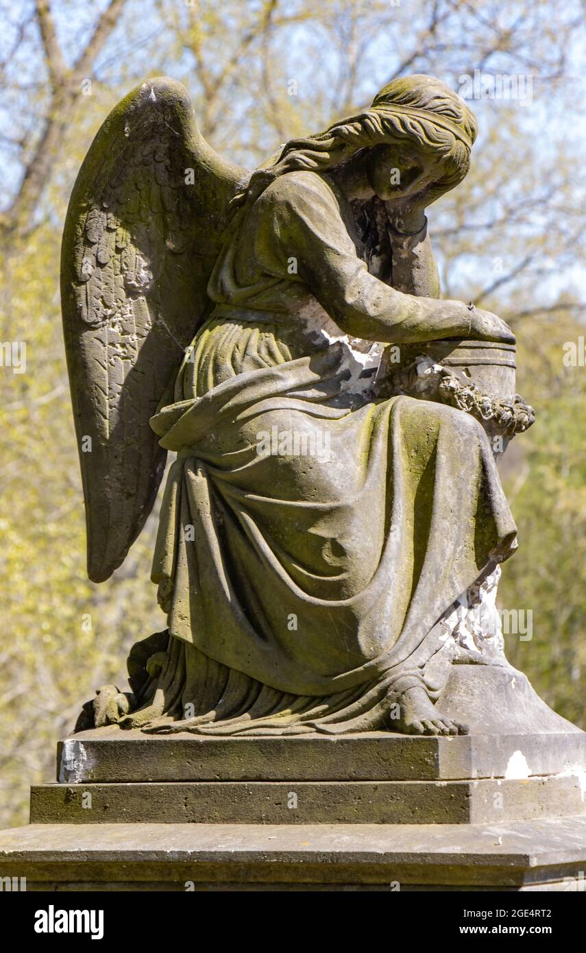 Eine Statue eines trauernden Engels an der Wand eines ländlichen Friedhofs. Stockfoto