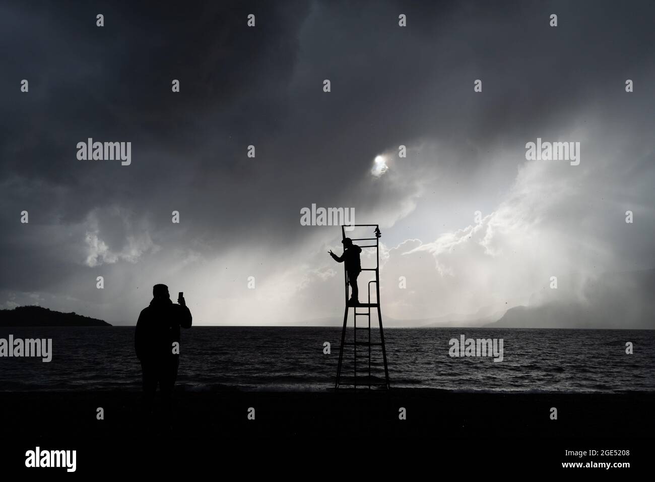Pucon, Araukanien, Chile. August 2021. Touristen fotografieren sich am Strand von Pucon, am ersten Tag eines Sturms, der von der Hauptstadt Santiago in den Süden Chiles angekündigt wurde. Es wird erwartet, dass es sich um den Hauptregen des Jahres in der südlichen Zentralzone Chiles handelt. (Bild: © Matias Basualdo/ZUMA Press Wire) Bild: ZUMA Press, Inc./Alamy Live News Stockfoto