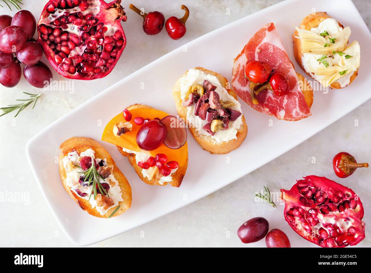 Auswahl an Crostini-Vorspeisen mit einer Vielzahl von Belägen. Oben Tischszene auf einem hellen Hintergrund. Party-Food-Konzept. Stockfoto