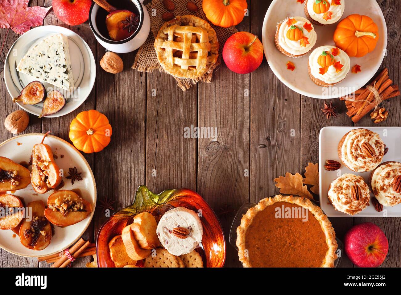 Herbstlicher Rahmen für Lebensmittel. Tischszene mit einer Auswahl an Torten, Vorspeisen und Desserts. Blick von oben auf einen rustikalen Holzhintergrund. Speicherplatz kopieren. Stockfoto