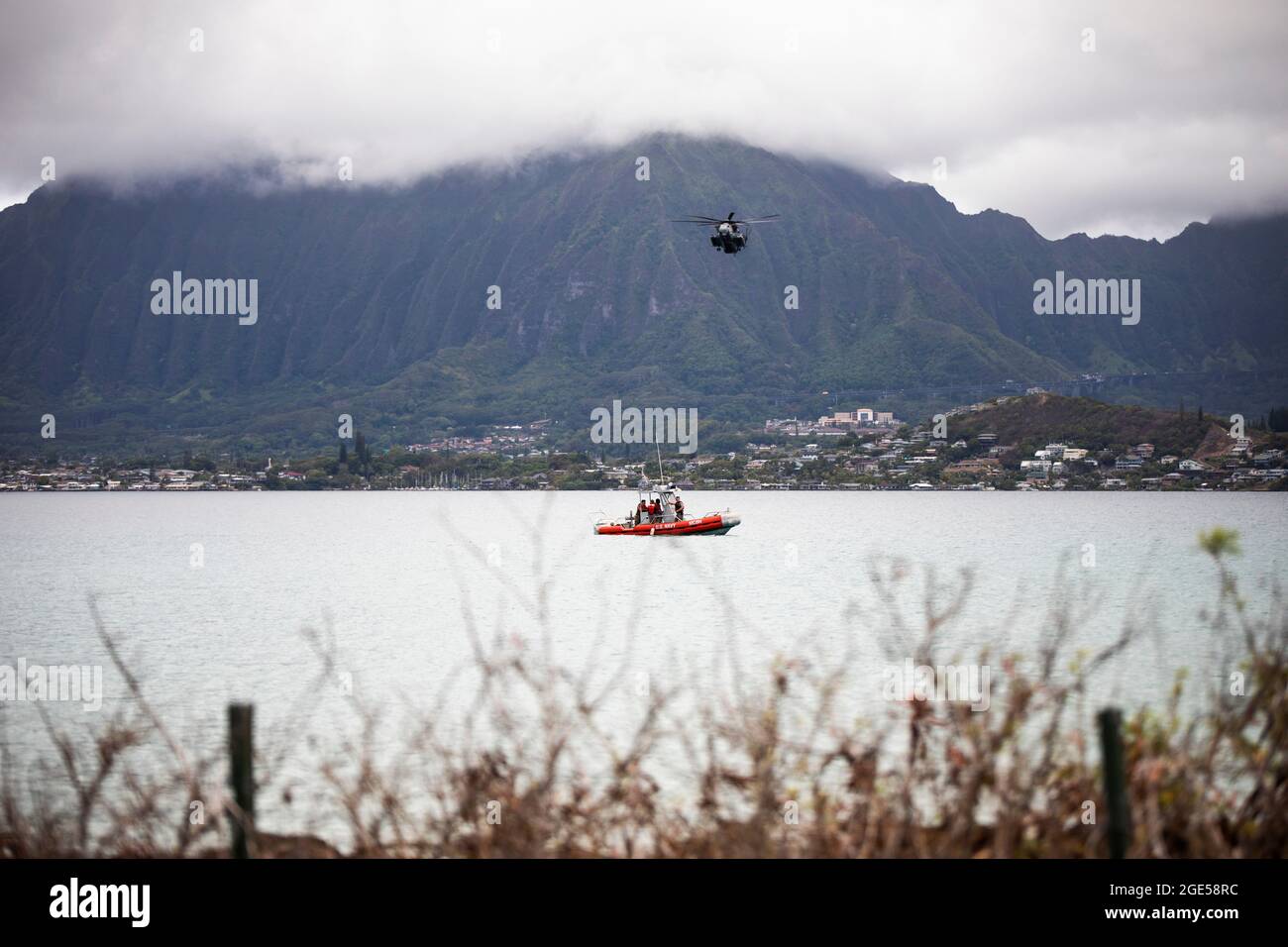 US-Militärpersonal mit dem Marine Corps Base Hawaii Provost Marshal’s Office und Waterfront Operations post Security on a marine vessel, während ein CH-53 Super Hengst, der an Marine Heavy Helicopter Squadron 463 befestigt ist, während Lethal Breeze 2021, MCBH, 10. August 2021, über Bord fliegt. Lethal Breeze ist eine Übung, die die Fähigkeit der Basis zeigt, während eines dynamischen Vorfalls effektiv zu reagieren, zu kommunizieren und Operationen über mehrere Standorte hinweg zu koordinieren. (USA Marine Corps Foto von Lance CPL. Brandon Aultman) Stockfoto