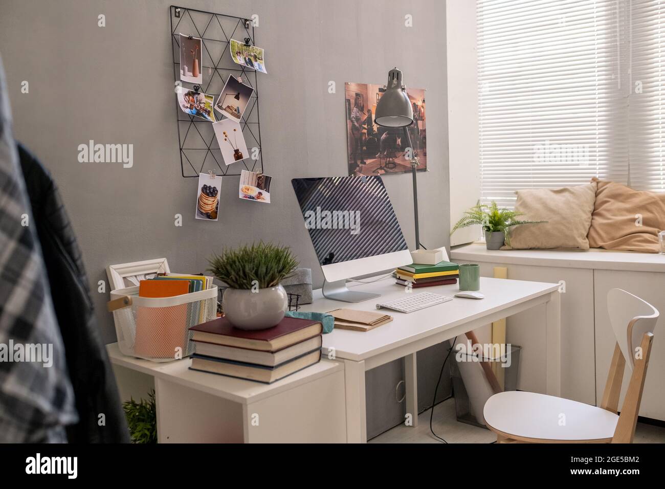 Die Inneneinrichtung eines Teils des Wohnzimmers mit Schreibtisch, Stuhl, Computer, Büchern, Lampe und anderen Dingen Stockfoto