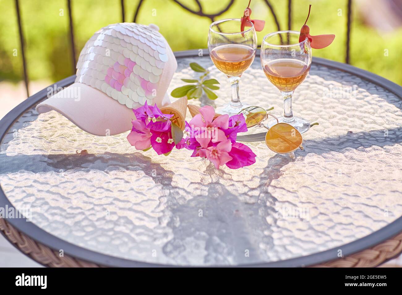 Gläser von rosafarbenem Wein, rosa Blüten von Bougainvillea und helle Frauenmütze. Sommer trendy kreative Konzept der Ferien. Hochwertige Fotos Stockfoto