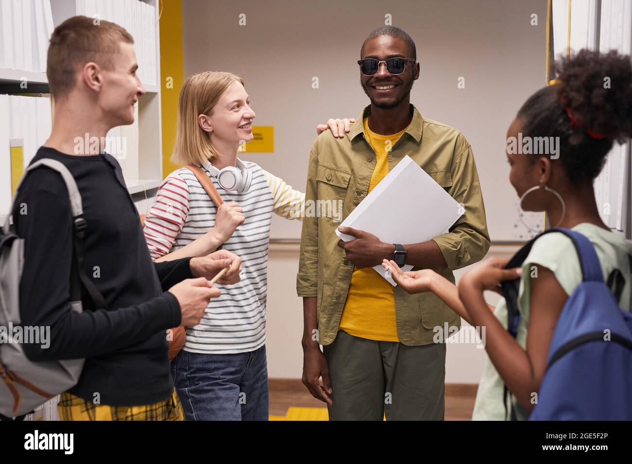 Waist-up-Porträt einer Gruppe von Studenten, die mit einem lächelnden Blinden chatten Stockfoto