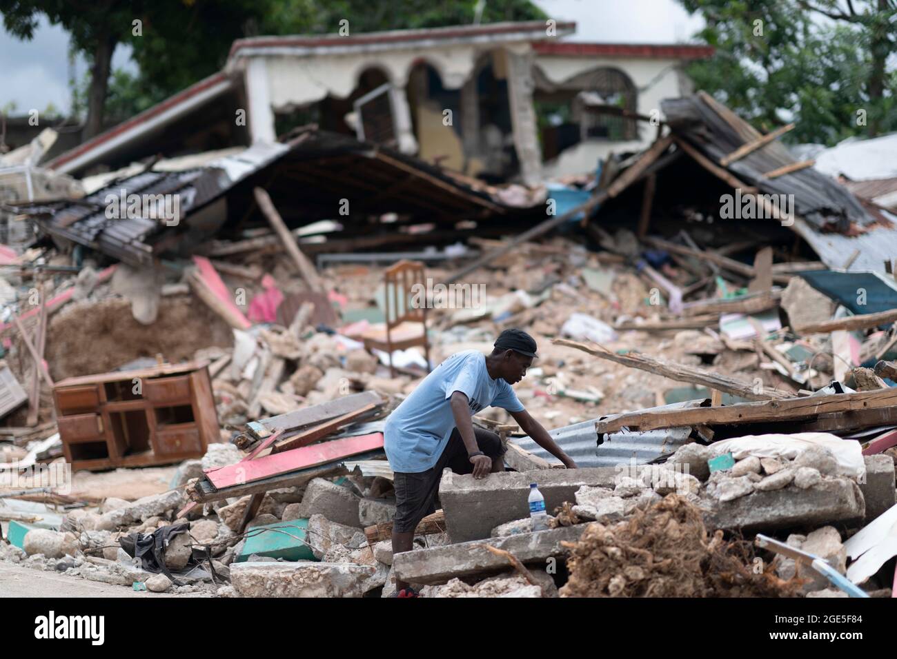 Les Cayes, Haiti. August 2021. Am 16. August 2021 sucht ein Mann in Les Cayes, Haiti, nach einem Erdbeben in den Trümmern eines eingestürzten Hauses nach. Die Zahl der Todesopfer durch das starke Erdbeben, das am Samstag den Südwesten Haitis heimsuchte, stieg auf 1,419, teilten die Behörden am Montag mit. Das Erdbeben der Stärke 7.2 hat außerdem mindestens 6,900 Menschen verletzt und mehr als 37,000 Häuser zerstört, so die Katastrophenschutzbehörde des Landes. Quelle: David de la Paz/Xinhua/Alamy Live News Stockfoto