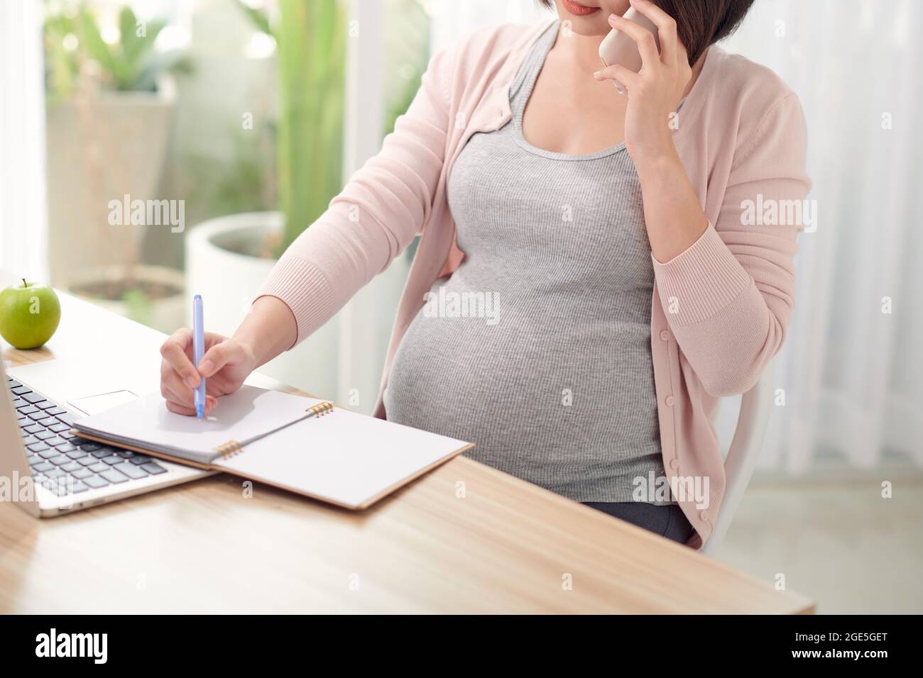 Schwanger asiatische Frau arbeitet von zu Hause in modernen weißen Büro Stockfoto