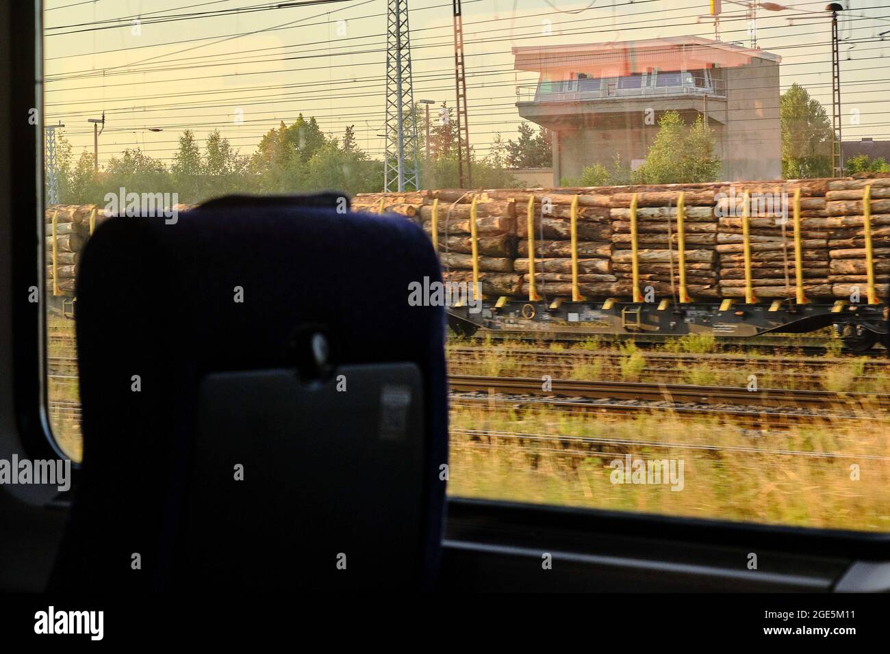 12. August 2021, Sachsen-Anhalt, ---: Blick von der fahrenden IC 2949 auf Waggons, die mit im Bahnhof geparkten Holzstämmen beladen sind. Laut einer Umfrage der GD Holz unter ihren Mitgliedsunternehmen erwartet die Mehrheit der teilnehmenden Unternehmen weiterhin steigende oder stabile Umsätze, wobei knapp ein Drittel auch mit rückläufigen Umsätzen rechnet. Der Holzhandel ist nach wie vor stark von Einschränkungen der Lieferbereitschaft oder Lieferfähigkeit vorgelagerter Lieferanten betroffen. Die angespannte Lage in der Lieferkette wird sich daher laut Bericht voraussichtlich in t fortsetzen Stockfoto