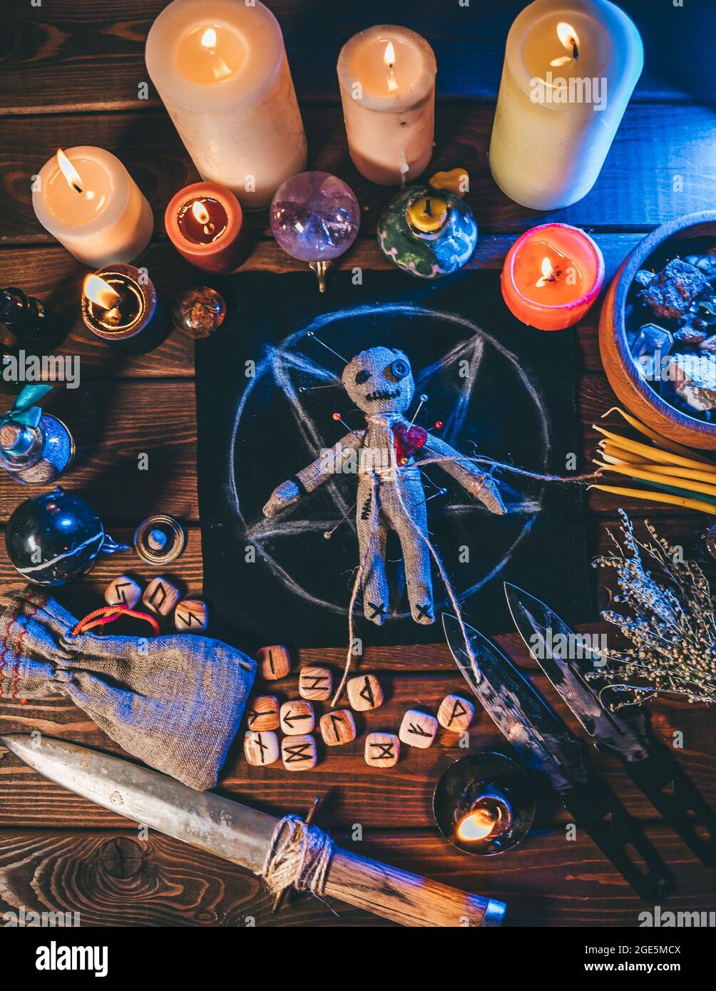 Voodoo Puppe auf Holztisch mit Kerzen und okkulten Objekten, Draufsicht. Magischer und dunkler gruseliger ritueller Hintergrund, vertikales Posterbild. Stockfoto